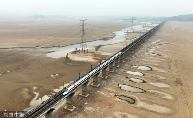 2022年9月22日，江西九江，一列动车组行驶在进入枯水期的九景衢铁路鄱阳湖铁路特大桥上。