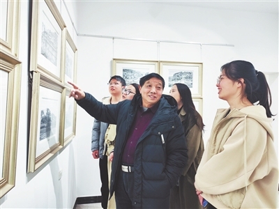 罗保根在美术馆内向参观者介绍自己创作的版画作品。