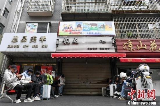 2025年1月8日，众多外地顾客提着行李箱等待李晓华的理发店开门。中新社记者 杨华峰 摄