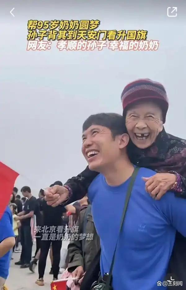 男子将奶奶托在肩头观看升旗仪式