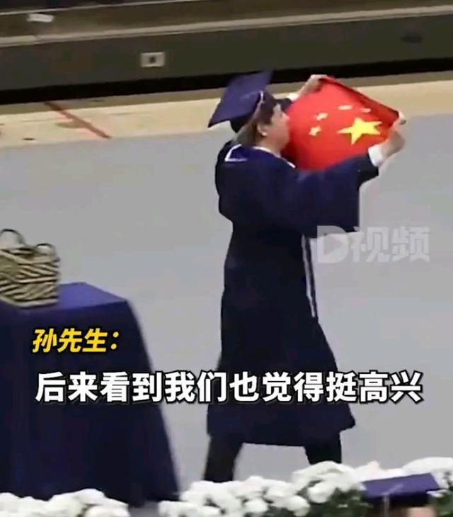 留学生举国旗参加毕业礼 老师微笑注视台下有欢呼声