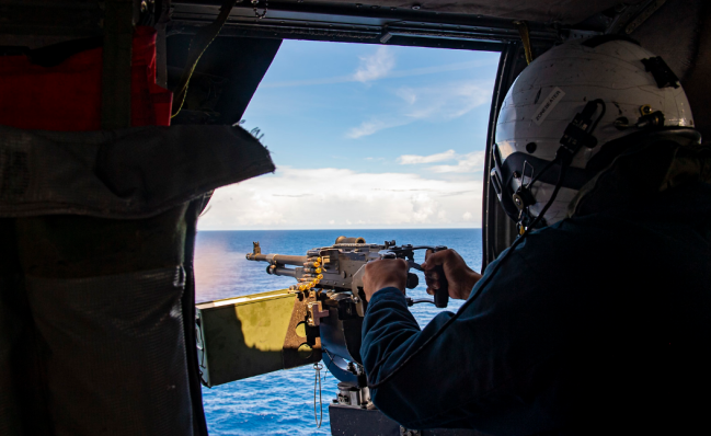 一艘濒海战斗舰在南海派出舰载直升机,瞄准海面开火射击