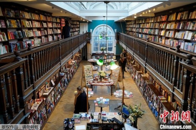 资料图：4月12日，英国伦敦但特书店重新开业，读者在店中浏览书籍。