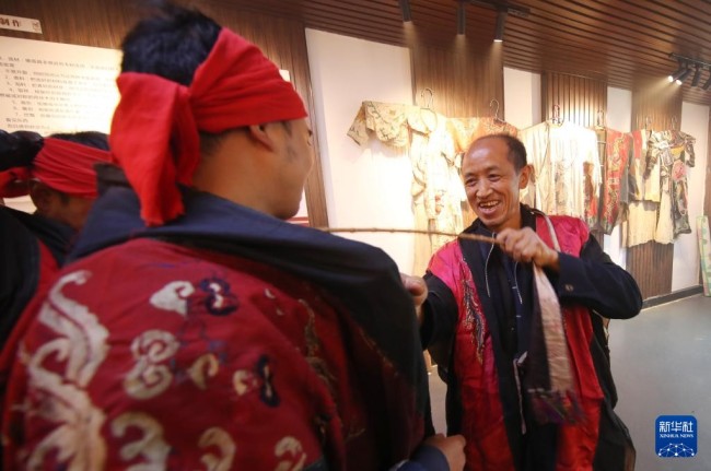 10月17日，在岑巩县平庄镇平庄村，肖光华（右）帮助徒弟穿上演出服装。