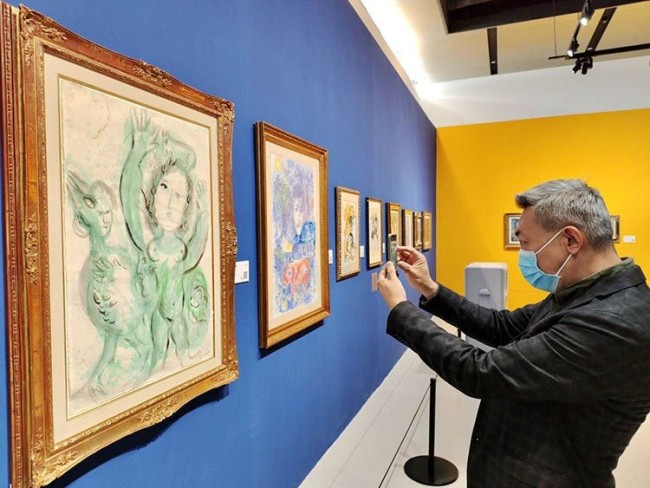 观众在拍摄夏加尔1964年纸本水彩作品《绿色的影像》。