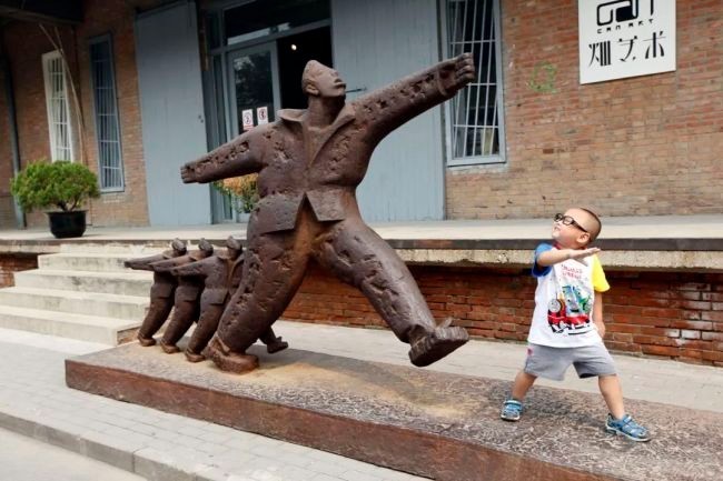 2012年，798艺术区内，一个可爱的小朋友在模仿雕塑的姿式。罗伟/摄