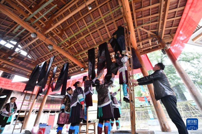 10月19日，在桂黔乌英苗寨亮布文化节上，苗族妇女在悬挂亮布。