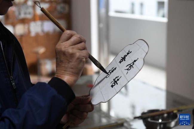 在广西桂林市灵川县定江镇，圆竹剖丝团扇制作技艺传承人黄硕夫在题写扇面（10月29日摄）。
