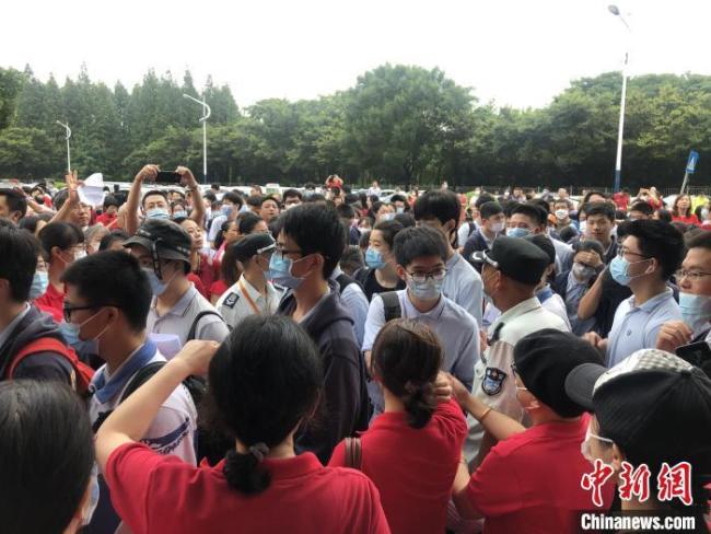 资料图：2020年全国高考期间，上海某考场外，老师们穿着红色T恤站在考场入口处为考生们送上祝福。　叶颖 摄