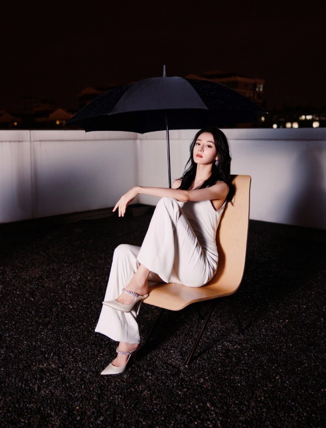 热巴穿斜肩连体裤撑黑伞 眼神霸气酷飒十足