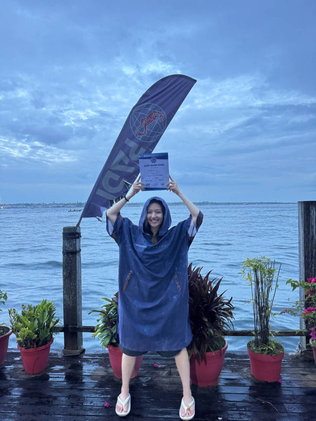 李兰迪拿着潜水证笑容灿烂 坐在海边素颜清秀