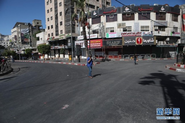  5月18日，人们经过约旦河西岸城市纳布卢斯街头关闭的店铺。 当日，约旦河西岸多个城市举行罢工，抗议以色列对加沙地带的空袭。
