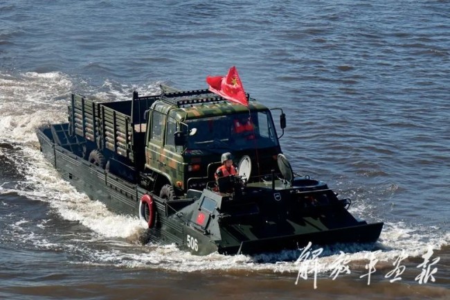 “开阔水域”项目比赛中，我军参赛队员驾驶两栖装甲车渡送运输车。