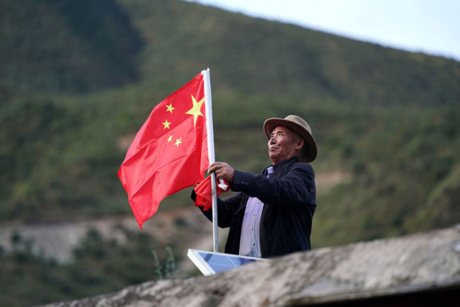 9月25日，在西藏昌都市江达县岗托村，普巴在屋顶上换上崭新的国旗，这是他每月进行一次的“仪式”。今年是昌都解放70周年，普巴说，现在我们的美好日子，是解放军用生命和鲜血换来的，这份恩情，我们不会忘记。新华社记者 詹彦 摄