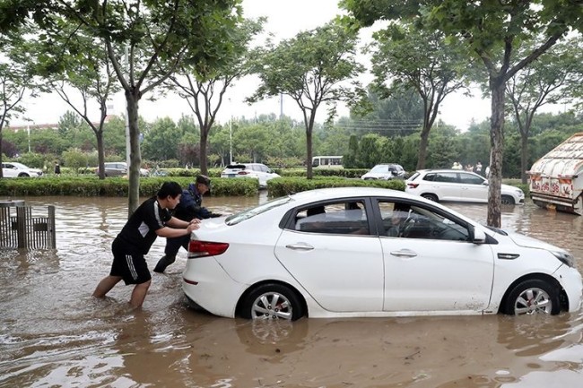 7月21日，郑州，救援队员帮助市民推涉水车辆。