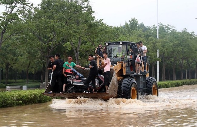 7月21日，郑州，市民王先生驾驶挖掘机满载被困群众。他自发前往积水区，已转移群众六十余名。