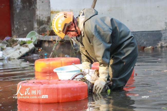 7月30日，河南省卫辉市健康路卫河河畔，消防员正在清理水上杂物。
