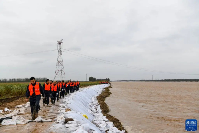 10月3日，在山东省邹平市码头镇段家村黄河生产堤上，抢险人员加固堤坝。图/新华网