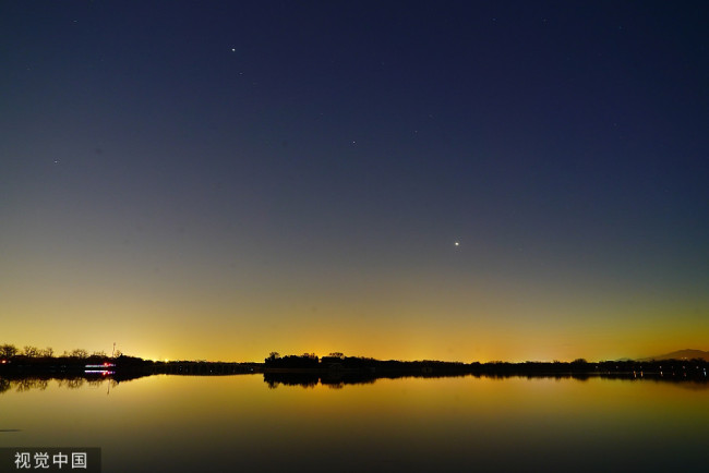 2021年12月4日，北京西南方低空，太阳落山后，颐和园昆明湖上空的金星如同明珠般美丽，似钻石般璀璨。明亮的金星与火红的落日余晖同框显得格外耀眼。当日，以“长庚星”姿态现身的金星迎来最亮时刻，这是观测金星的最佳时机。“届时，金星的亮度可达-4.9等，视亮度为8年来之冠。收起