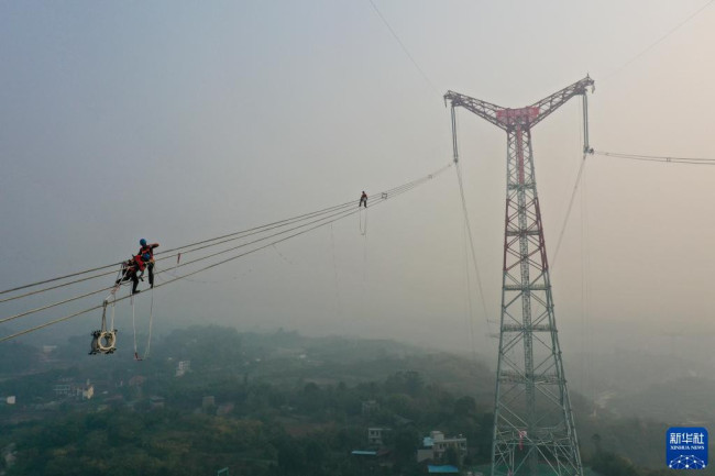12月5日，在白鹤滩—江苏±800千伏特高压直流输电线路工程（重庆段）江津长江大跨越施工现场，工人在长江上空作业（无人机照片）。
