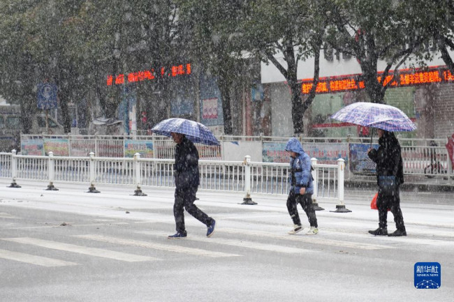 12月26日，在贵州省丹寨县县城，人们在雪中行走。