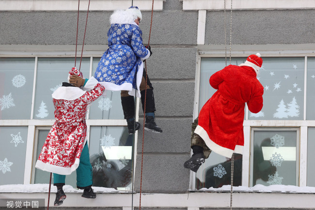 当地时间2021年12月30日，俄罗斯新西伯利亚，当地救援队装扮成圣诞老人空降儿童医院窗前，探望生病孩童并送去圣诞祝福。