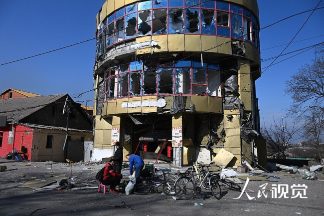 当地时间2022年4月5日，乌克兰马里乌波尔，当地民众在被炮弹摧毁的建筑附近行走。