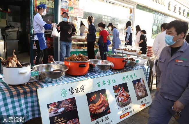 2022年5月14日，北京，市民在熟食店外购买食品。为保障北京市民健康安全，切实防范疫情传播风险，北京餐饮经营单位继续暂停堂食服务，转为外卖服务。
