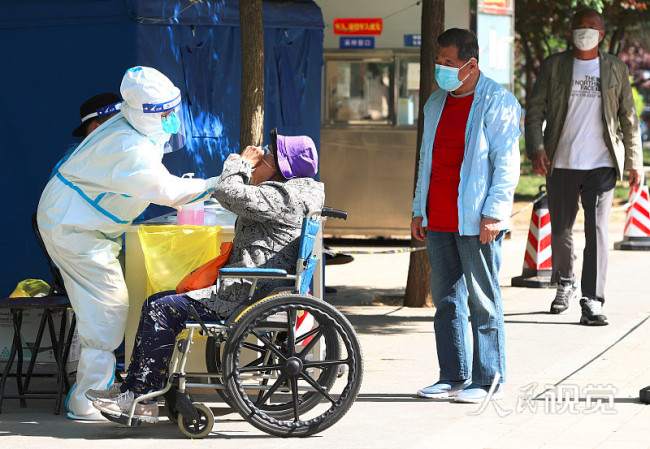 2022年5月15日，一位坐輪椅的老年人在北京市朝陽區的一處核酸檢測采樣工作站進行咽拭子采樣。