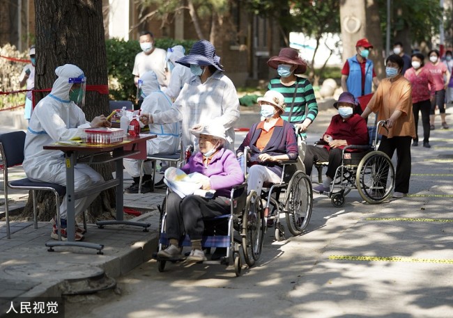 2022年5月22日，北京，海淀区永定路街道太平路46号社区西院，居民们在临时搭建的核酸检测点进行核酸检测。社区的党员干部和居家的在职党员作为志愿者为居民服务。