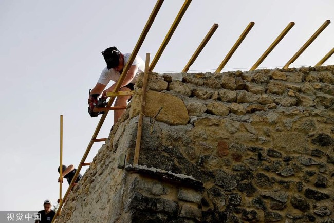 当地时间2022年6月16日，法国Haux，建筑工人在修复一座房子。热浪持续席卷城市，工人们为免受高温影响，将工作安排在傍晚进行。