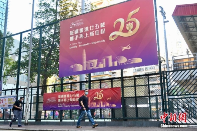 6月24日，随着香港回归祖国25周年纪念日临近，香港九龙的旺角、太子、深水埗多区随处可见庆祝香港回归祖国25周年的横幅、海报等，喜庆气氛浓。图为旺角一街头的庆回归广告。 中新社记者 李志华 摄