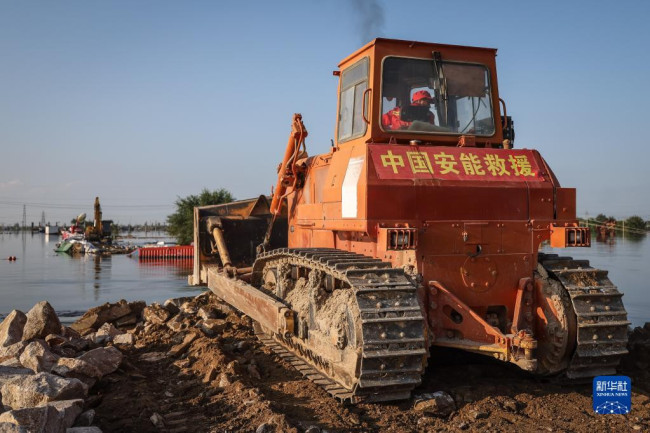 8月5日，中国安能集团抢险人员在溃口处驾驶推土机进行封堵作业。