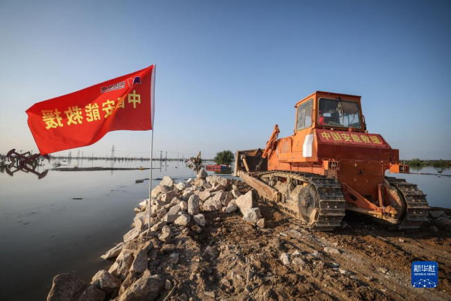 8月5日，中国安能集团抢险人员在溃口处驾驶推土机进行封堵作业。
