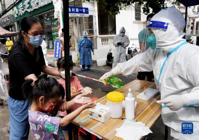 8月11日，在三亚市天涯区南边海渔村，河南省援海南三亚医疗队的医护人员原清怡为群众消毒。
