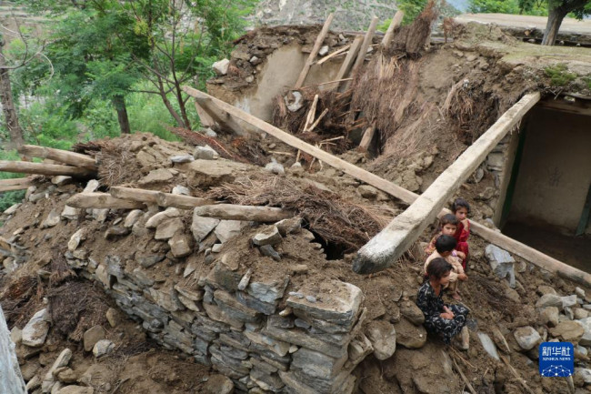 8月18日，孩子们坐在阿富汗努里斯坦省被洪水损毁的房屋废墟上。