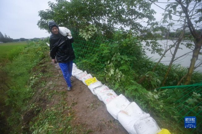 9月14日，在浙江省嘉兴市嘉善县陶庄镇湖滨村，防汛人员搬运沙袋加固河堤，防止台风引起的河水倒灌。新华社记者 徐昱 摄