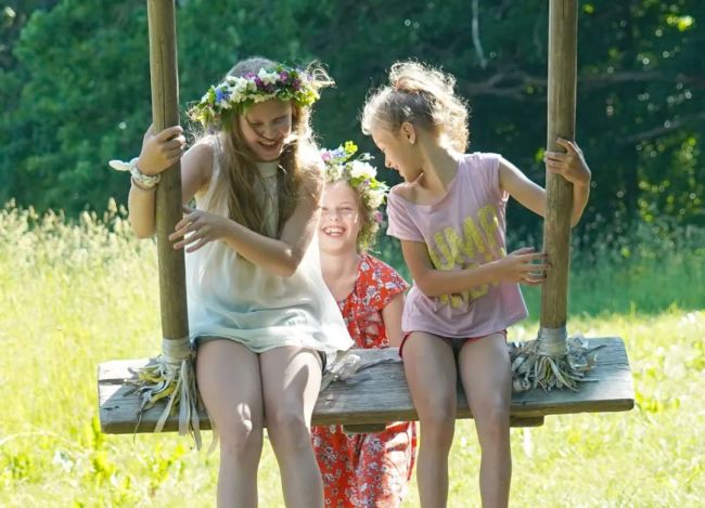 2020年6月21日，头戴花冠的女孩们在拉脱维亚乡村增特内的草坪上玩耍。新华社发（亚尼斯摄）