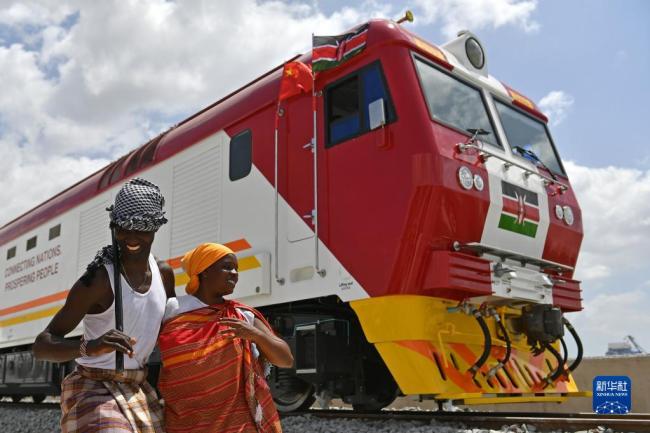 在肯尼亚蒙巴萨，当地民众在中国承制的蒙内铁路首批内燃机车旁载歌载舞（2017年1月11日摄）。新华社记者孙瑞博摄