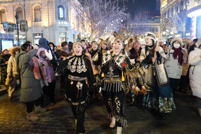 1月6日，身着赫哲族服饰的赫哲族群众在哈尔滨中央大街上与游客互动。