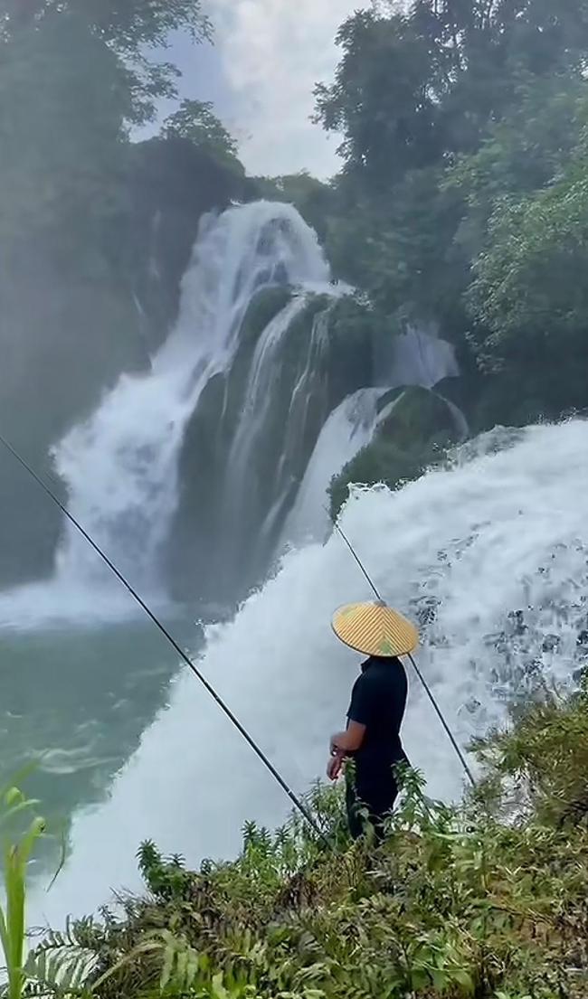 越南一男子站在德天跨国大瀑布上钓鱼 边境奇景引热议