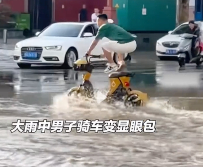 男子为不弄湿脚站在电动车上骑车