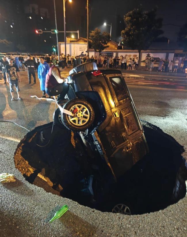 路面塌陷小车栽入坑中 路人破窗救人