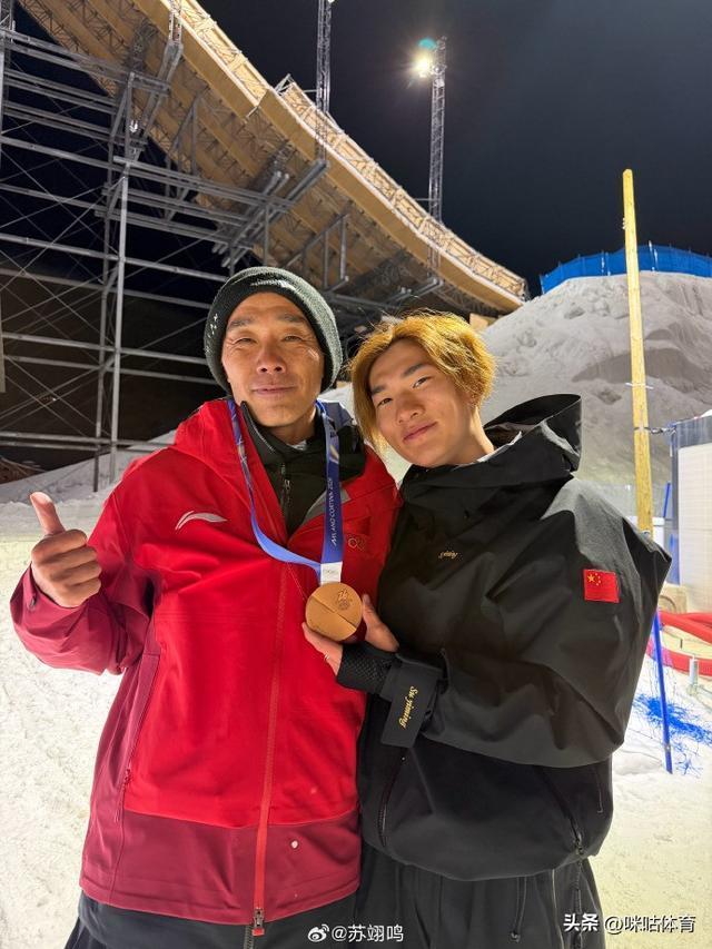 苏翊鸣一手挽着爸爸一手拎着奖牌