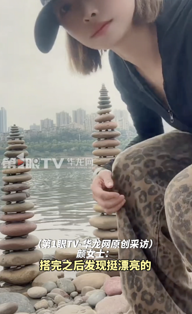 女生在江边搭石头塔垒到三十三层