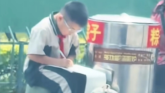 小男孩坐三轮车上写作业刷屏