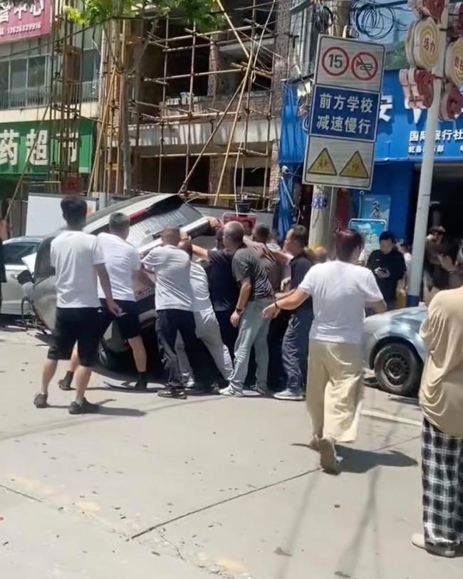 电动车骑手被困车下 众人抬车救人 女子不幸身亡