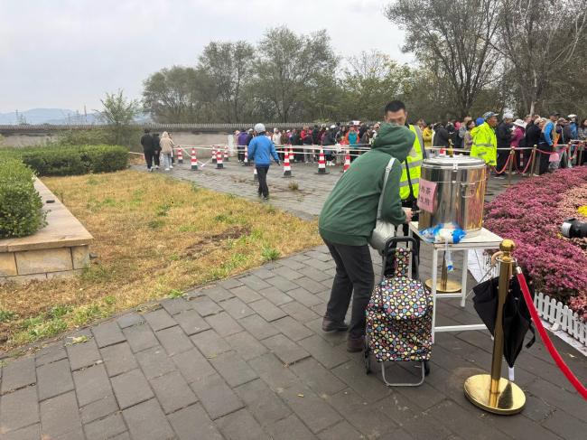 北京上百位市民雨中排队 接国庆鲜 花香传递节日温情
