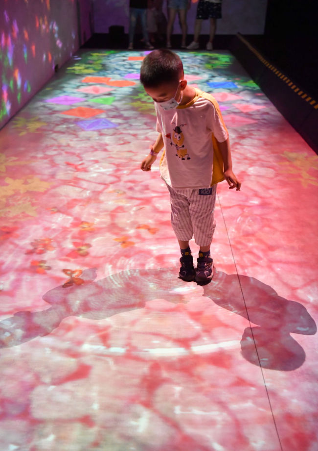 6月6日，在科技艺术节的“teamLab Future Park”未来游乐园中，一名小朋友在观察脚下泛起的“涟漪”。