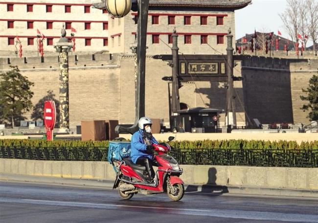 1月12日，在西安城墙永宁门外，外卖员骑行送货。 记者 董剑南摄